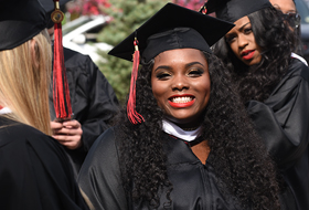 Female student smiling and wearing cap and gown on graduation day at La Roche University